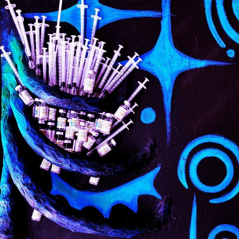 a blue paper mache ribcage containing syringes and vials of testosterone on a background of big, blue graphic style stars.